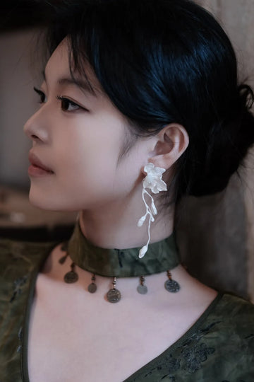 Woman wearing AOKINSIDE botanical sterling silver drop earrings with sculpted flowers and slender stems.