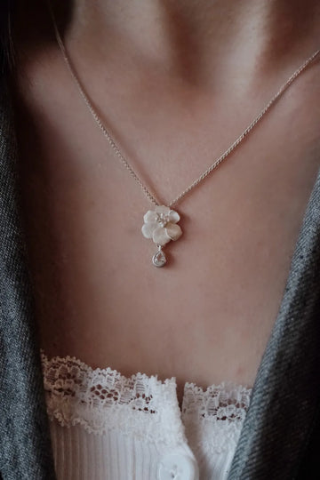 Close-up of an AOKINSIDE sterling silver flower pendant necklace with a clear teardrop accent.