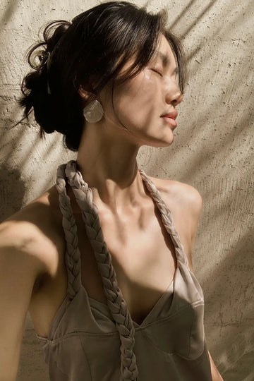 Woman wearing AOKINSIDE organic sterling silver statement earrings in warm natural light.