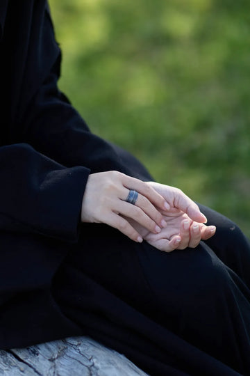Close-up of a woman wearing an AOKINSIDE textured oxidized sterling silver wide band ring outdoors.